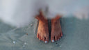 Bare feet in wet sand at the water's edge