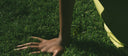 Hand pressed into green grass during an outdoor workout