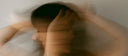 Blurred motion portrait of a woman holding her head, menopause brain fog